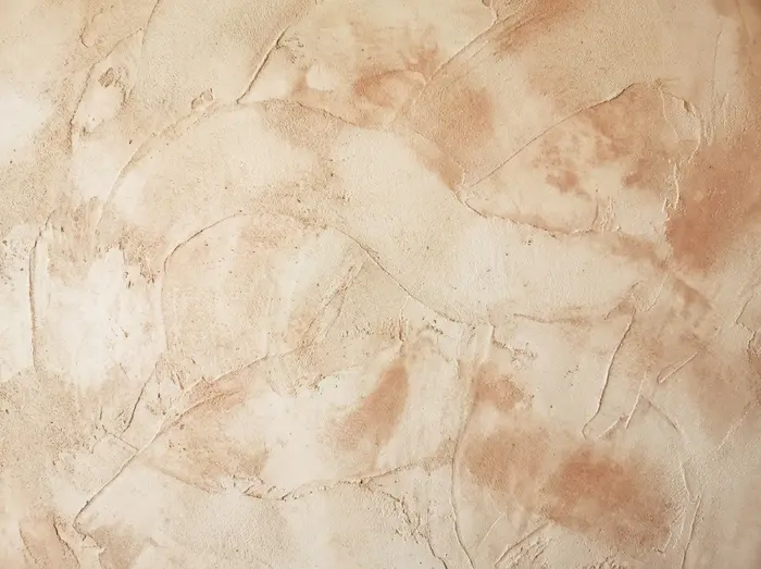 Close-up texture of a hand-applied plaster or lime-wash finish, with visible trowel marks in a warm neutral tone