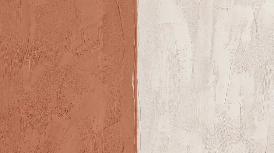 Macro close-up of a freshly cut-in paint edge where deep clay terracotta meets chalk white in a clean, knife-straight vertical line, with visible roller nap texture and a small run of wet sheen along the line